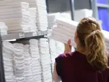 Member of staff loading fresh laundry onto shelf