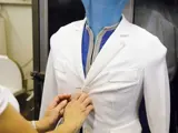 Member of staff adjusting a white workwear jacket to be cleaned