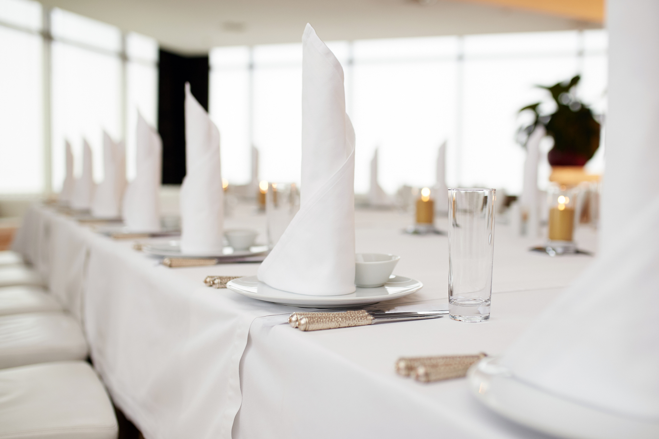 dinner set arranged on a table with vintage cream lace tablecloth and napkins, elegant porcelain dishes, silverware and crystal glassware